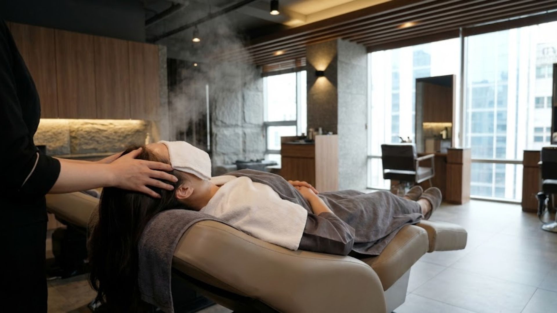 고급스러운 헤어 살롱에서 편안하게 누워 헤드스파 관리를 받고 있는 30대 여성의 모습